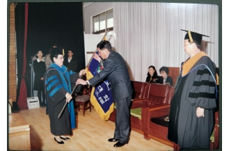 학장이취임식에서 이영선 초대학장으로부터 신임 학장에게 전달할 교기를 받고 있는 김조영 이사장(1999)